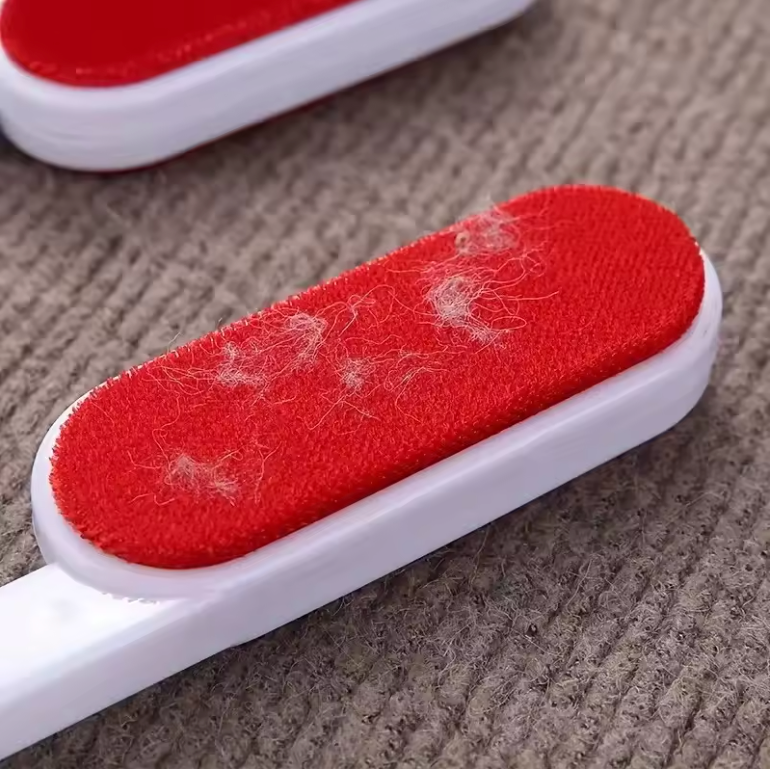 Red and white pet hair tool with pet hair on a carpet surface