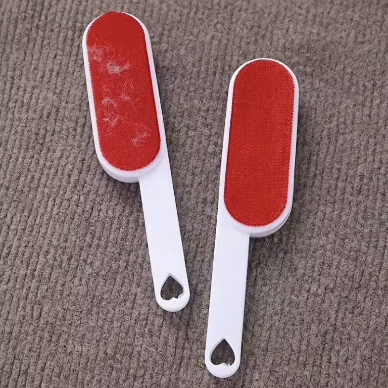 Two red and white pet hair brushes on a textured surface